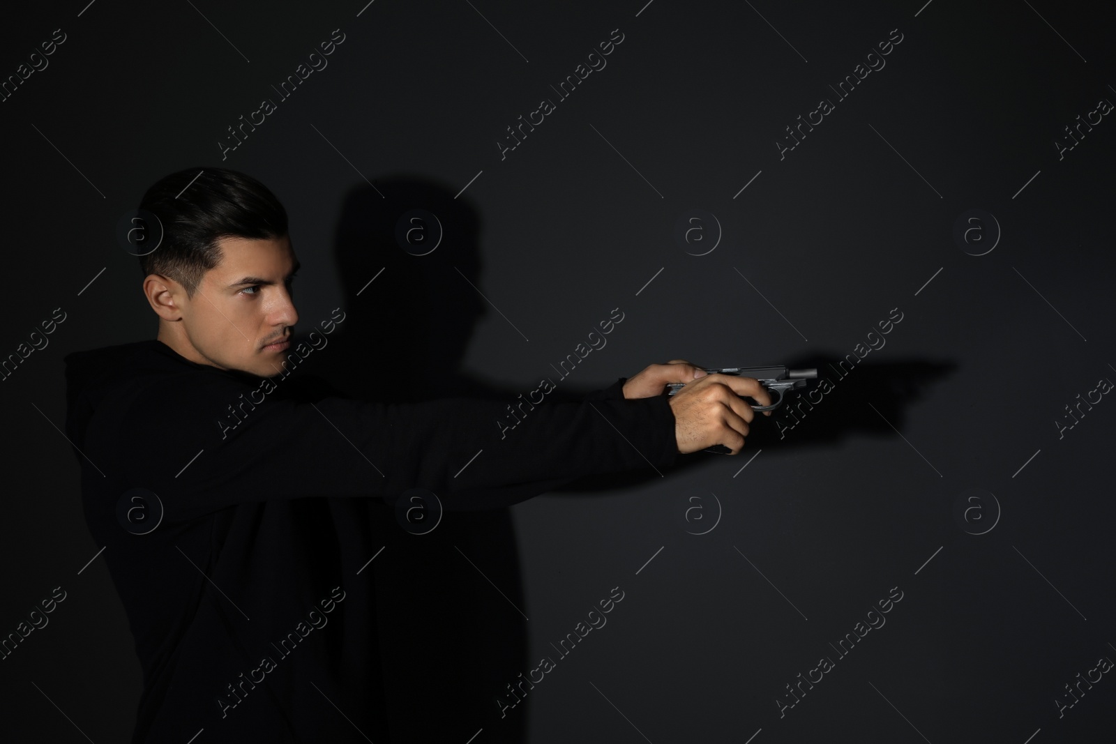 Photo of Professional killer with gun on black background