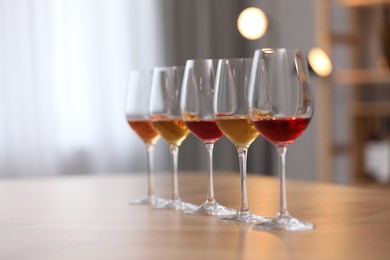 Photo of Different sorts of wine in glasses on wooden table indoors. Space for text