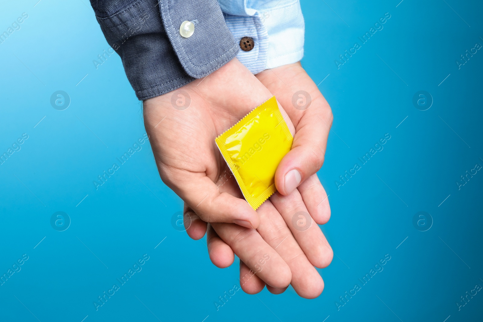 Photo of Gay couple with condom on light blue background, closeup