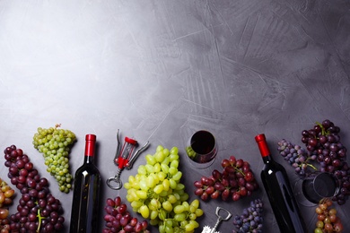 Flat lay composition with fresh ripe juicy grapes and wine on grey table, space for text