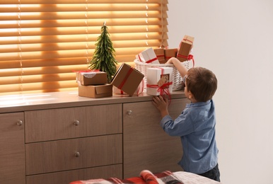 Photo of Little boy with Christmas gifts at home. Advent calendar in basket