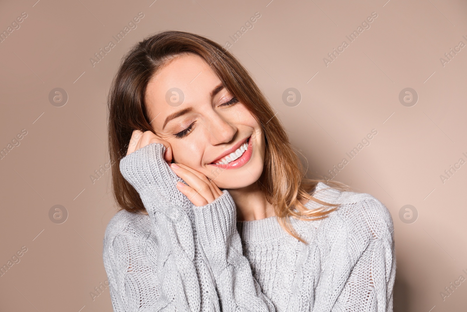 Image of Happy young woman wearing warm sweater on beige background 