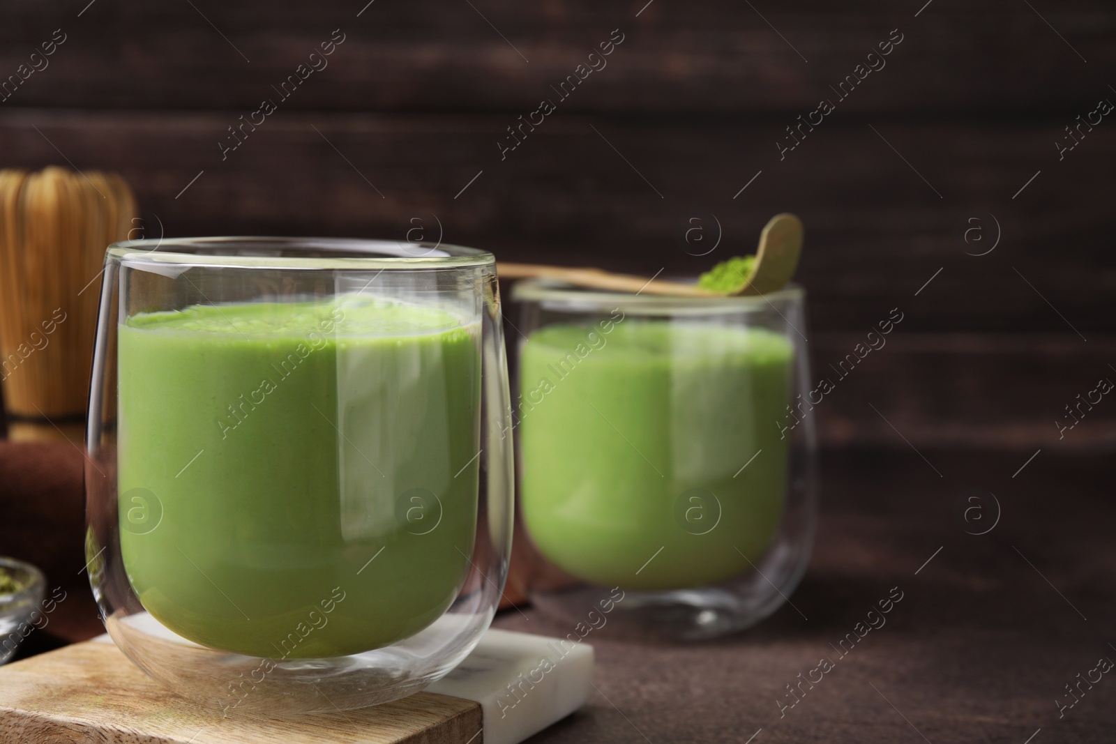 Photo of Glass of tasty matcha smoothie on brown table, closeup. Space for text