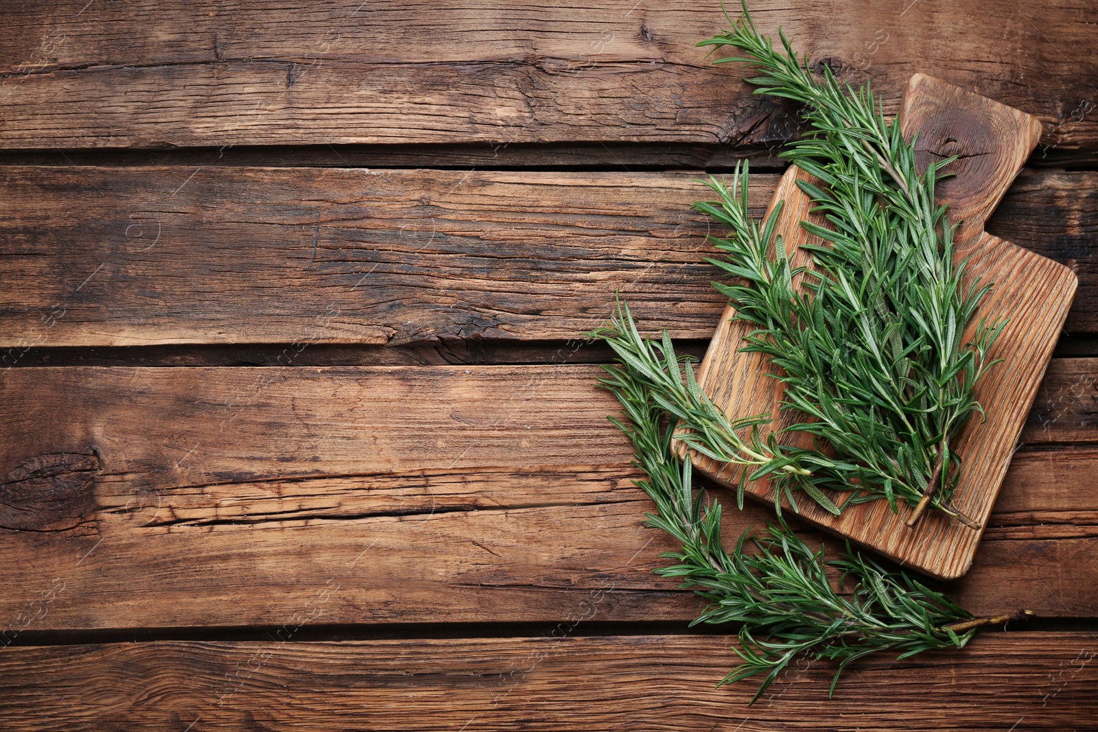 Photo of Fresh rosemary on wooden table, flat lay. Space for text