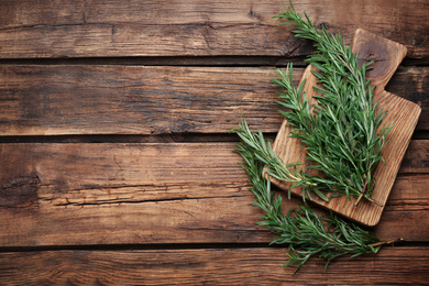 Photo of Fresh rosemary on wooden table, flat lay. Space for text