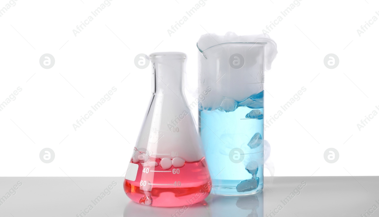 Photo of Laboratory glassware with colorful liquids and steam isolated on white. Chemical reaction