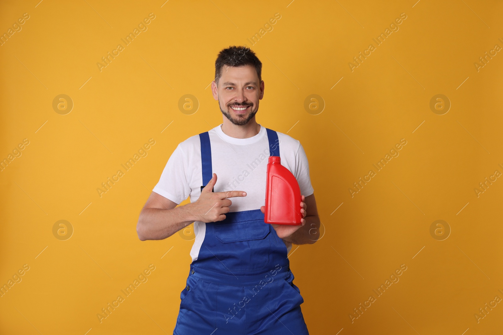 Photo of Man pointing at red container of motor oil on orange background