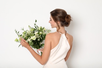 Photo of Young bride wearing wedding dress with beautiful bouquet on light background