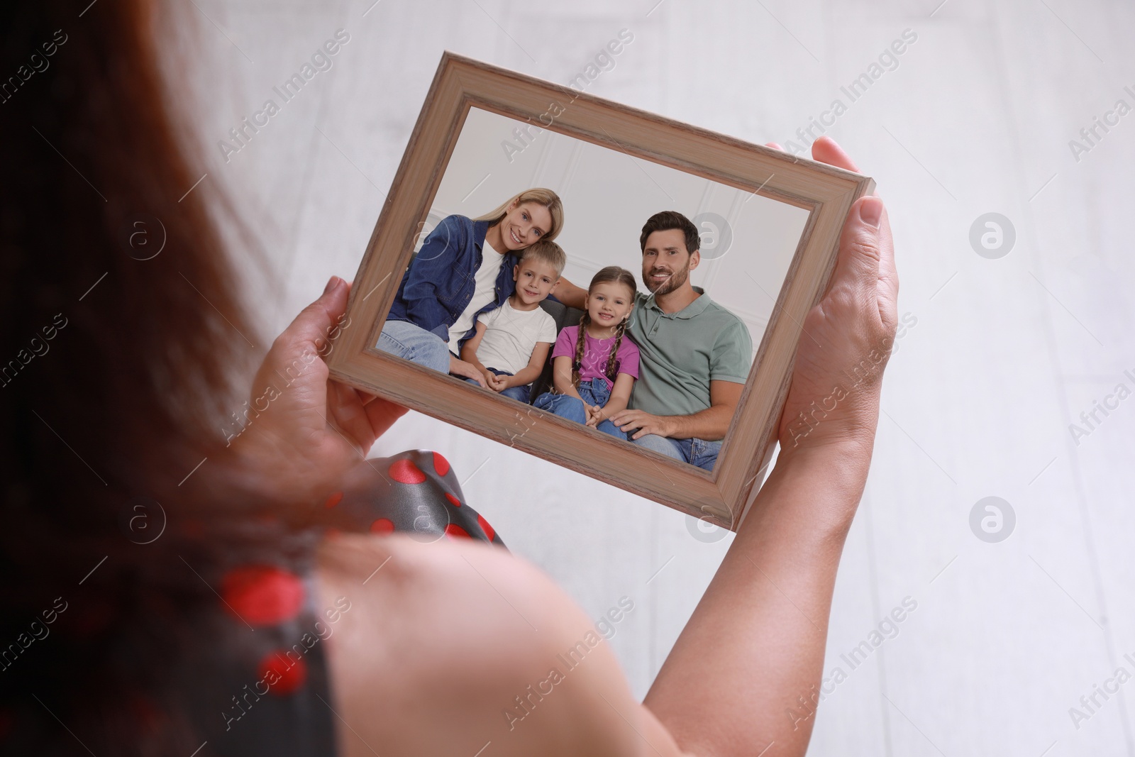 Image of Woman holding frame with photo portrait of her family indoors, closeup