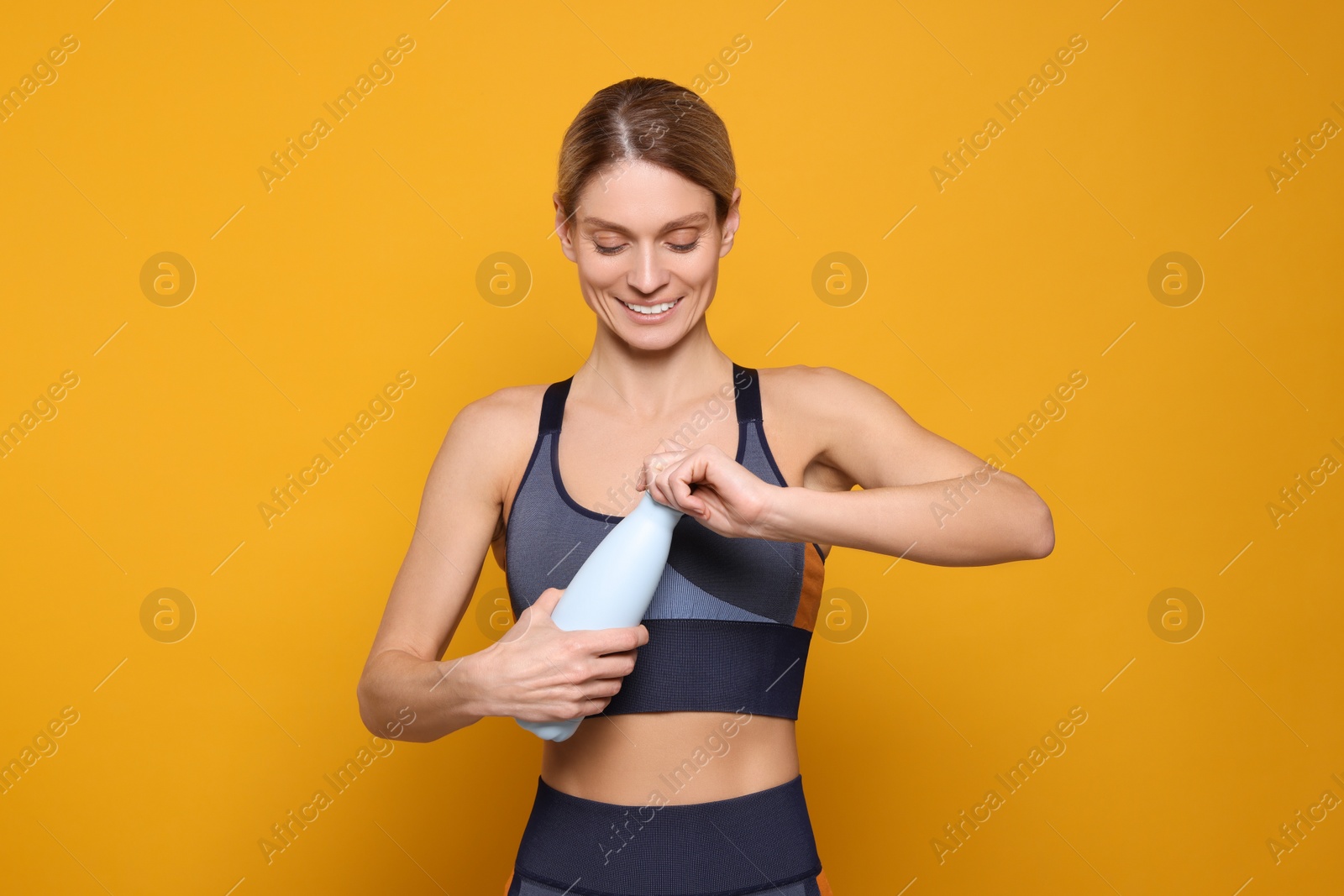 Photo of Sportswoman with thermo bottle on yellow background