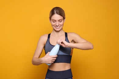 Sportswoman with thermo bottle on yellow background