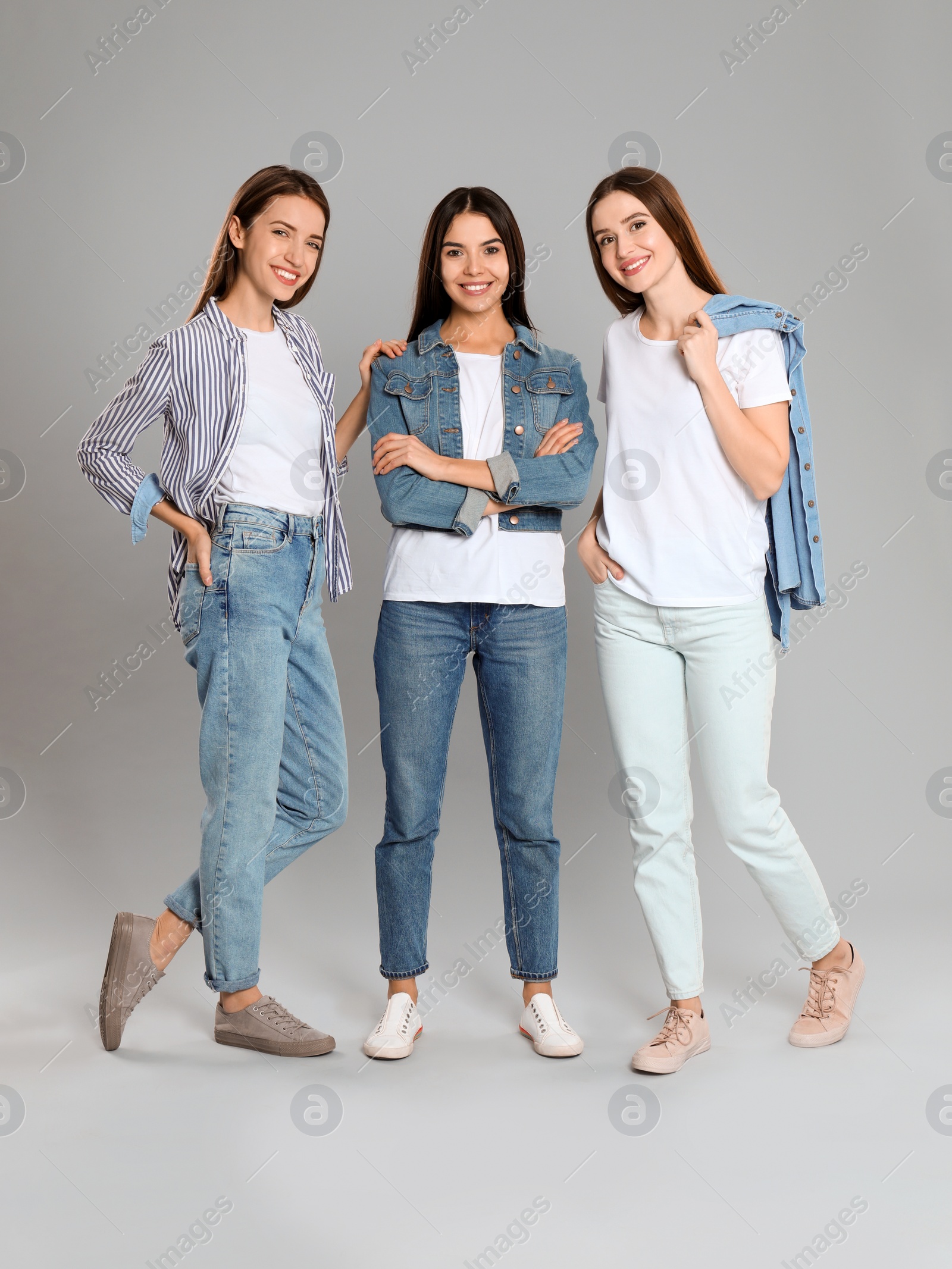 Photo of Group of young women in stylish jeans on grey background