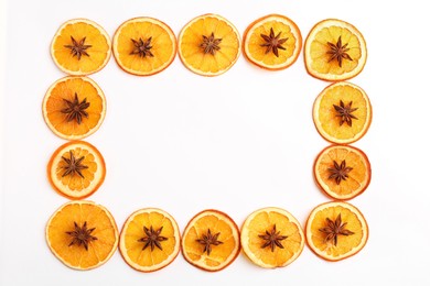 Photo of Frame made of dry orange slices and anise stars on white background, flat lay. Space for text