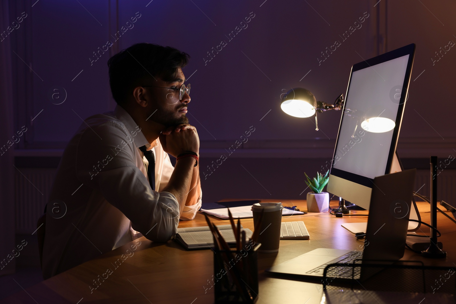 Photo of Tired young man working late in office