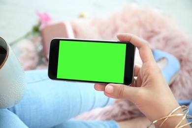 Chroma key compositing. Woman holding smartphone with green screen indoors, closeup. Mockup for design