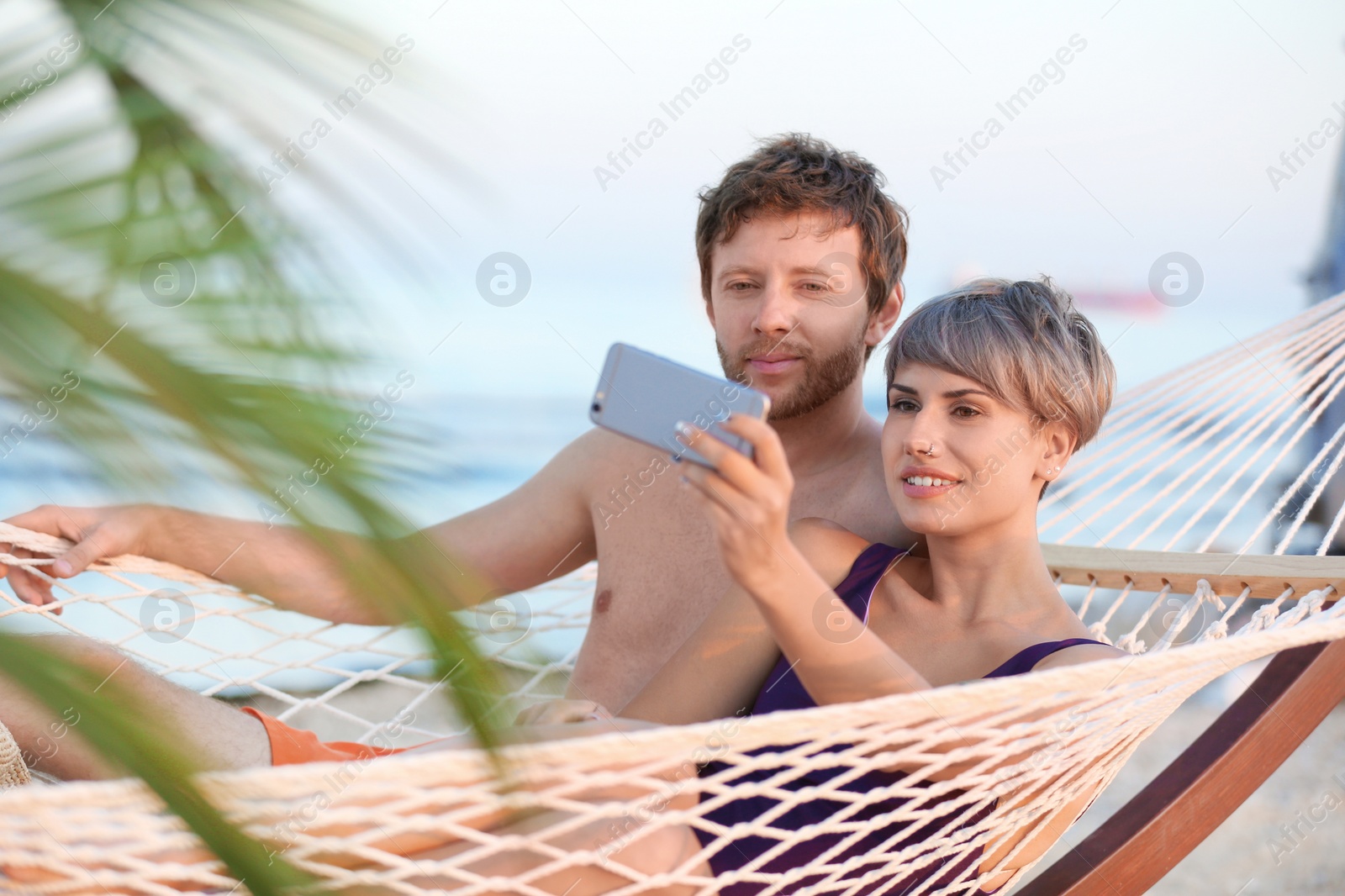 Photo of Young couple taking selfie in hammock on beach