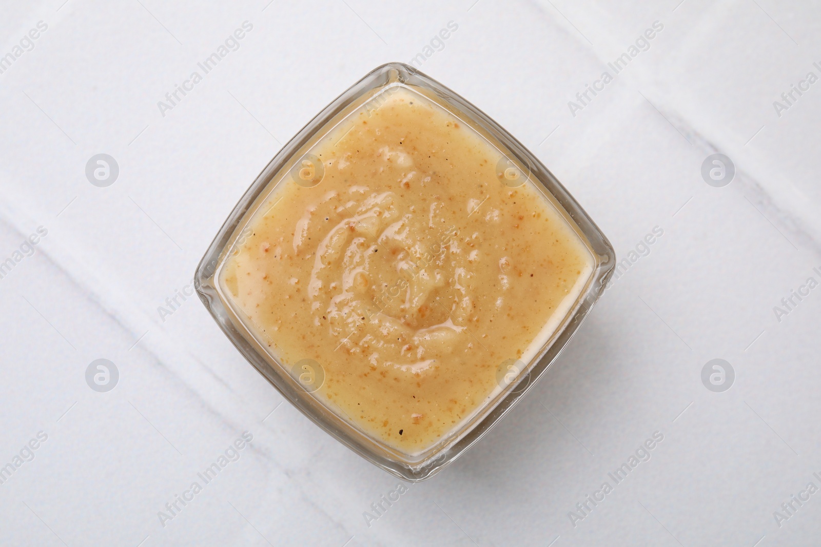 Photo of Delicious turkey gravy on white tiled table, top view