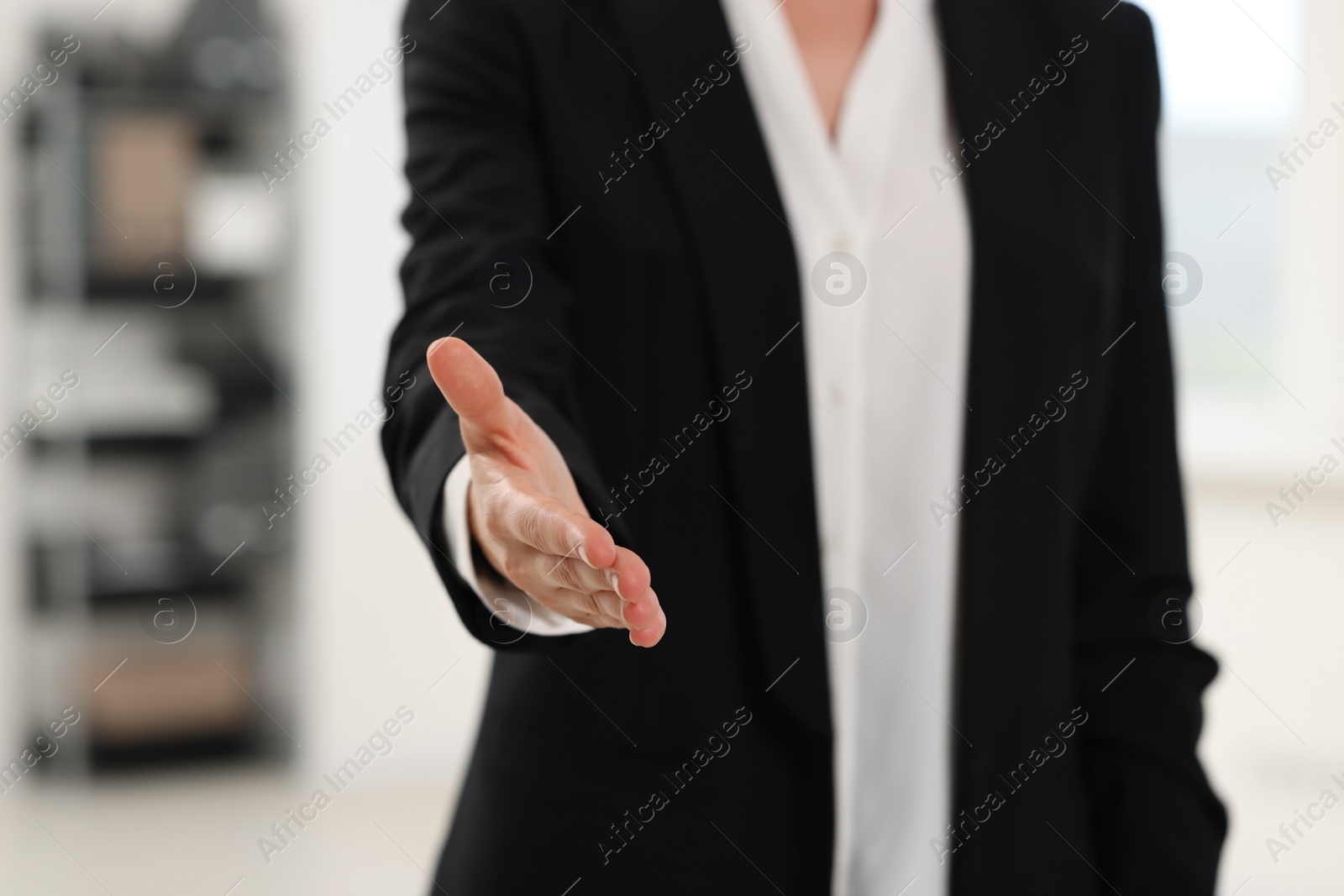 Photo of Woman welcoming and offering handshake indoors, closeup