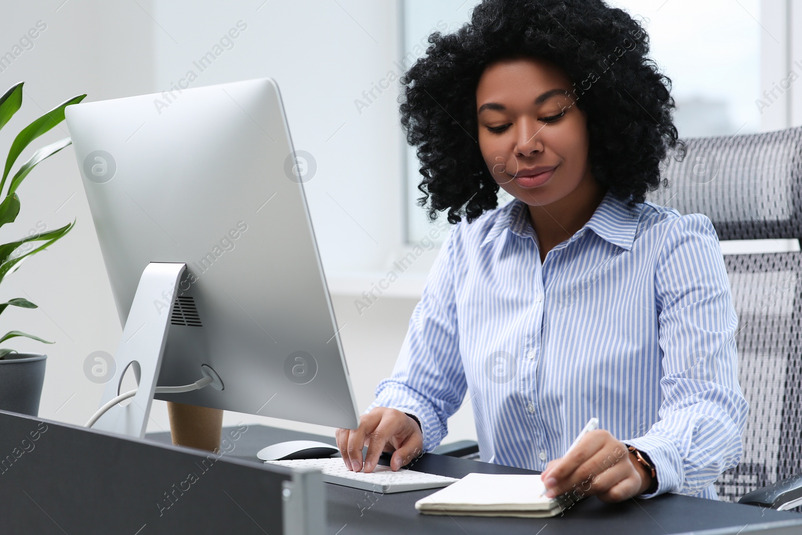 Photo of Young woman working on computer at table in office