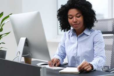 Young woman working on computer at table in office