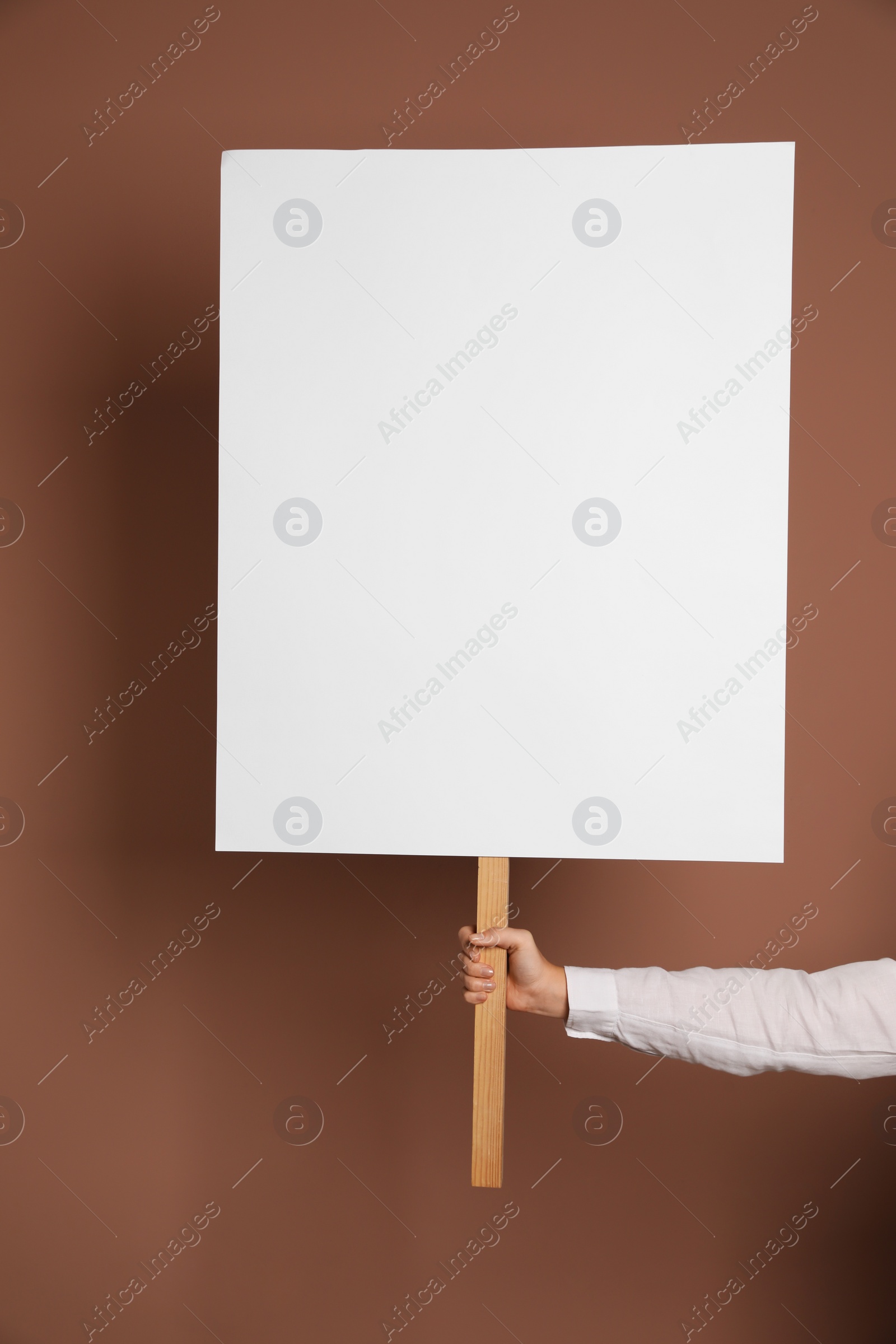 Photo of Woman holding blank sign on brown background, closeup. Space for design