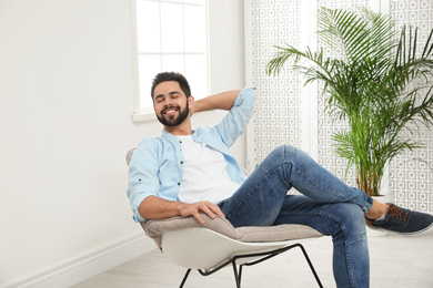 Photo of Young man relaxing in rocking chair at home