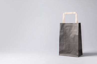 Photo of Black paper bag on light grey background, space for text