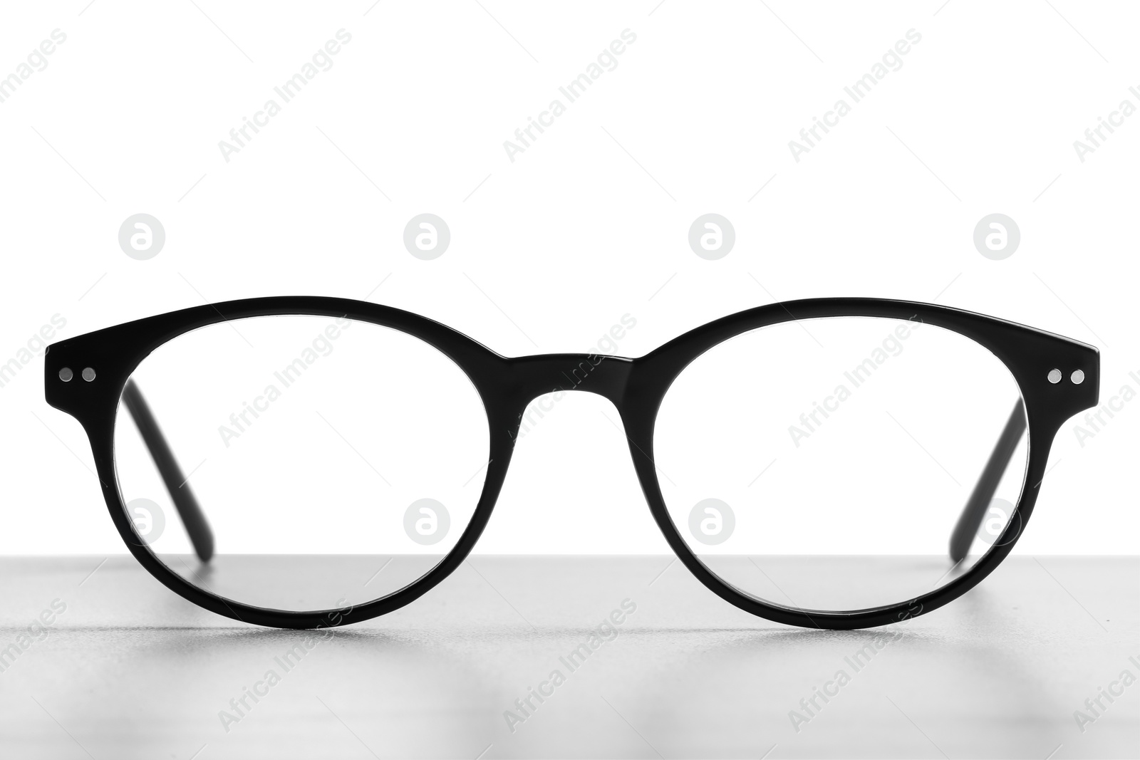 Photo of Stylish glasses with black frame on table against white background