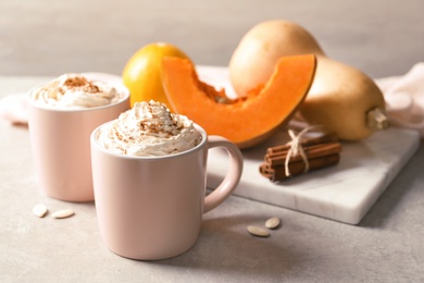 Photo of Cups with tasty pumpkin spice latte on gray table