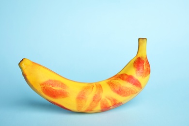 Fresh banana with red lipstick marks on blue background. Oral sex concept