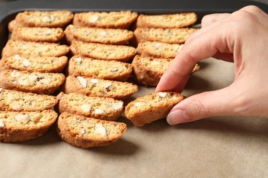 Photo of Woman taking traditional Italian almond biscuit (Cantucci) from baking sheet, closeup