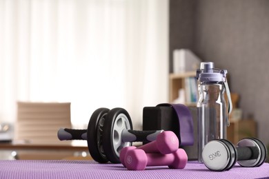 Many different sports equipment on mat indoors