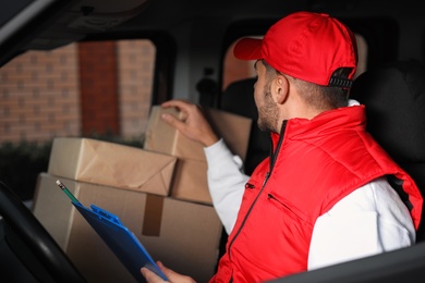 Photo of Deliveryman with clipboard and parcels in car