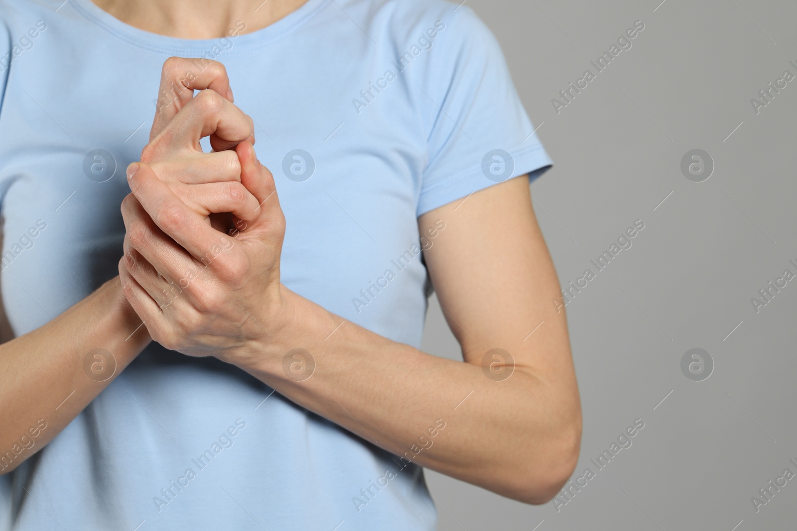 Photo of Woman cracking her knuckles on light grey background, closeup and space for text. Bad habit