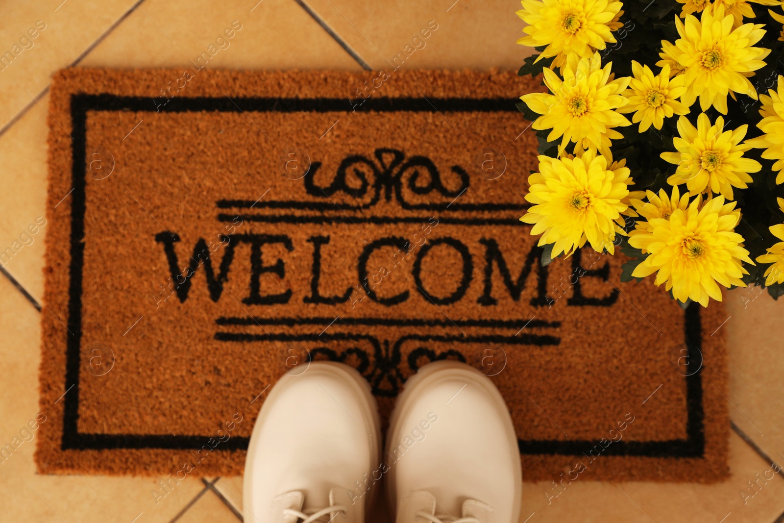 Photo of Door mat with word Welcome, stylish boots and beautiful flowers on floor, flat lay