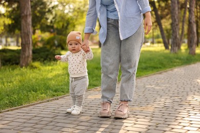 Photo of Mother supporting her baby while he learning to walk outdoors, closeup