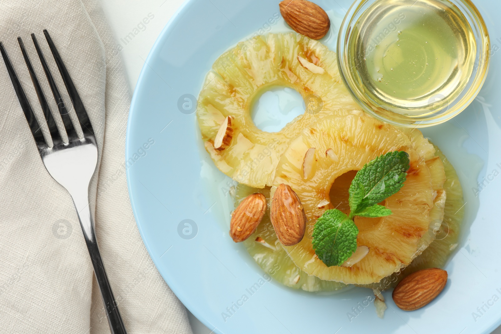 Photo of Tasty grilled pineapple slices served with mint, almonds and honey on white table, flat lay