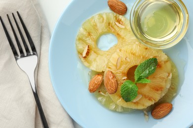 Photo of Tasty grilled pineapple slices served with mint, almonds and honey on white table, flat lay