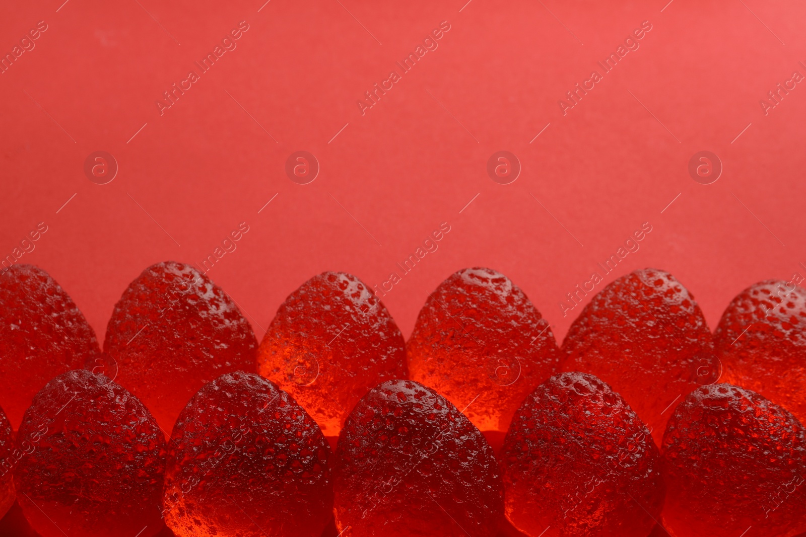 Photo of Delicious gummy strawberry candies on red background, above view. Space for text