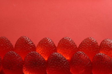 Photo of Delicious gummy strawberry candies on red background, above view. Space for text
