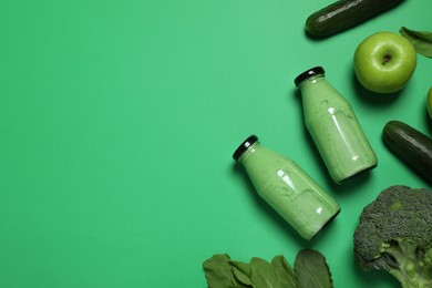 Photo of Bottles of delicious smoothie and ingredients on green background, flat lay. Space for text