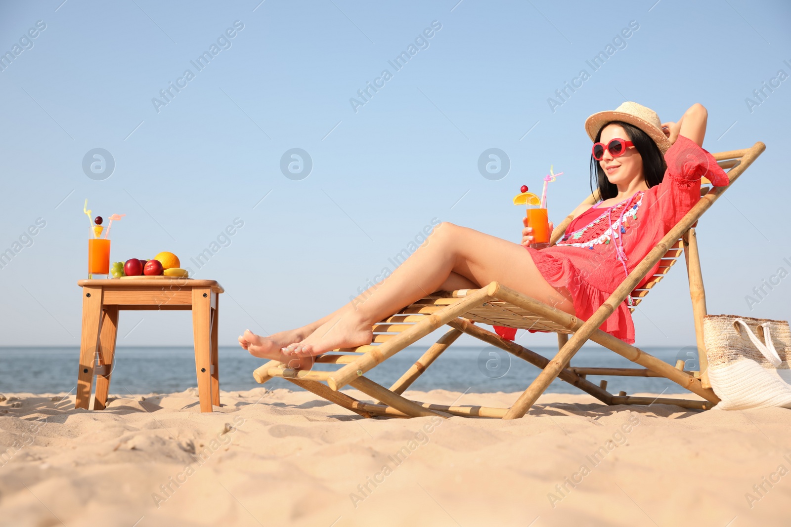 Photo of Beautiful woman in red dress resting on beach