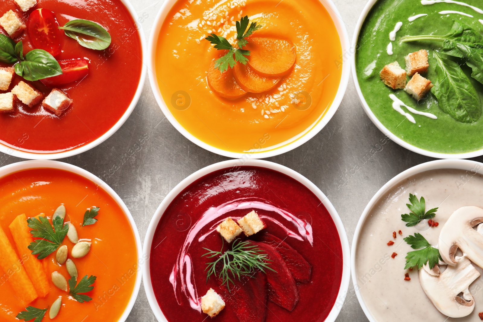 Photo of Various cream soups in bowls on grey background, top view