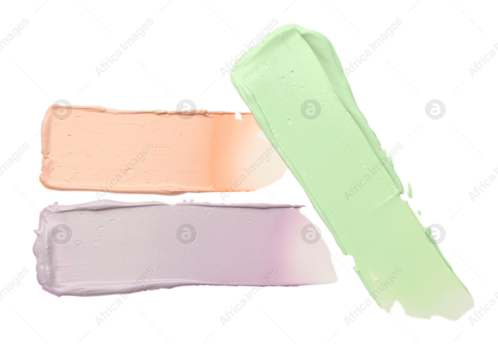 Photo of Strokes of pink, green and purple color correcting concealers isolated on white, top view