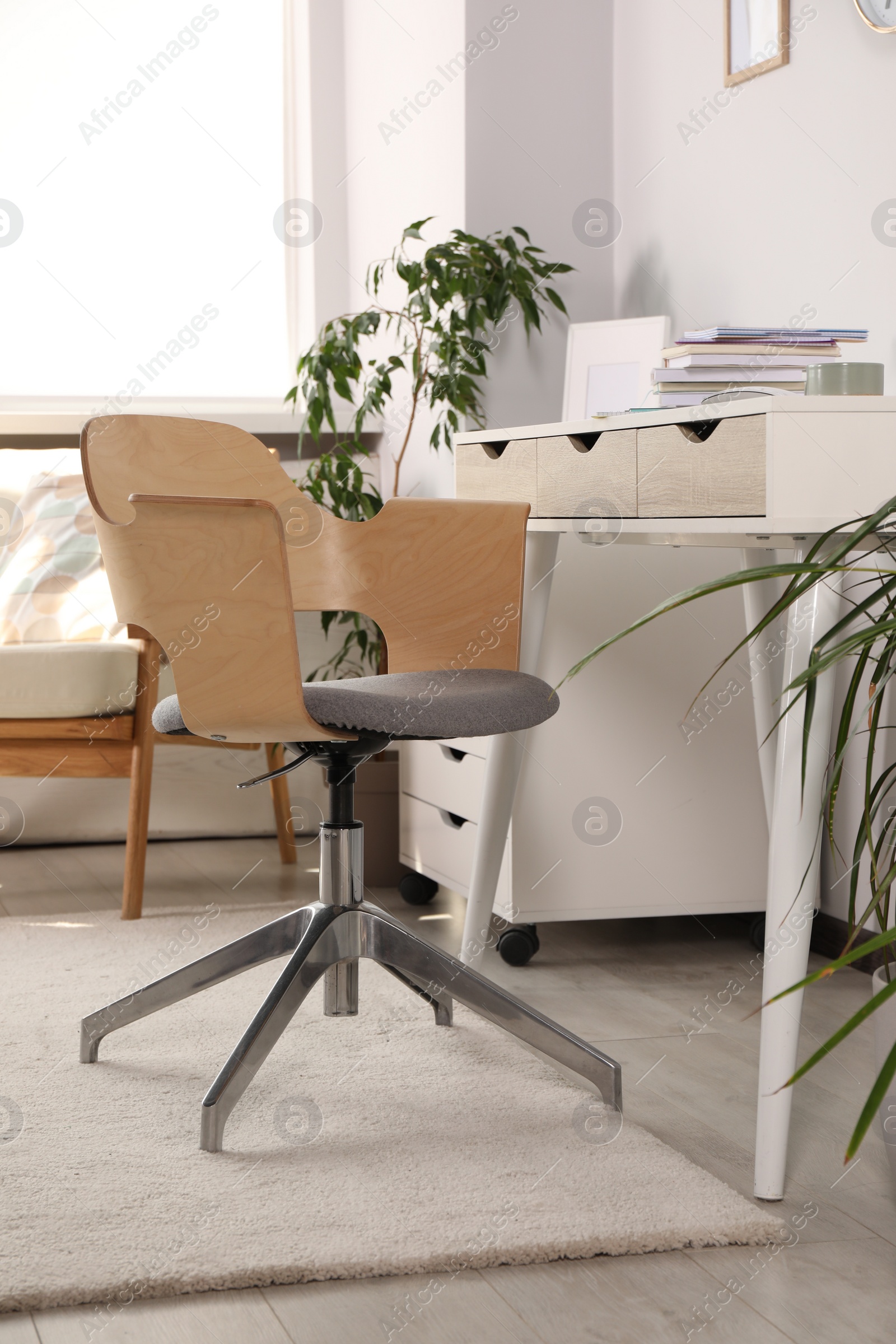 Photo of Beautiful workplace with laptop on white wooden table, chair and houseplants in room