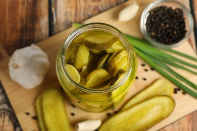 Photo of Jar with tasty pickled cucumbers and ingredients on wooden table, closeup