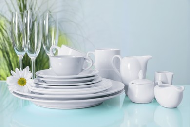 Photo of Set of clean dishware and flower on light blue table