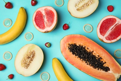 Photo of Flat lay composition with condoms and exotic fruits on turquoise background. Erotic concept