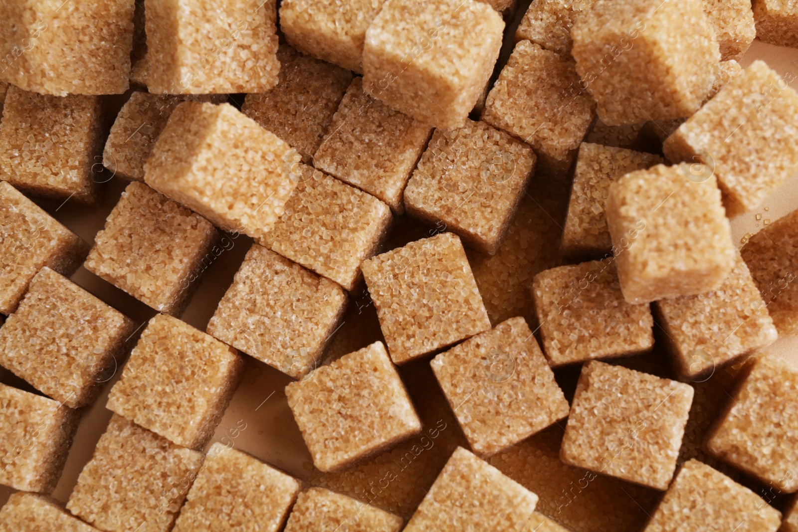 Photo of Brown sugar cubes on color background, top view