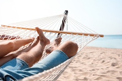 Photo of Young couple relaxing in hammock on beach, closeup